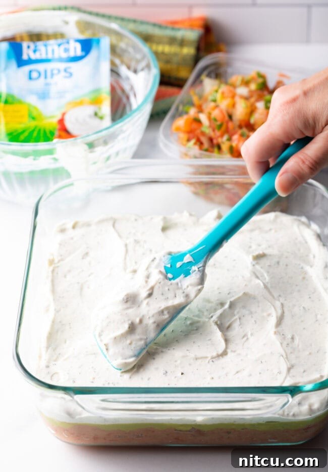 Fiesta Bean Stack 8 Hand with blue spatula spreading cream layer on.