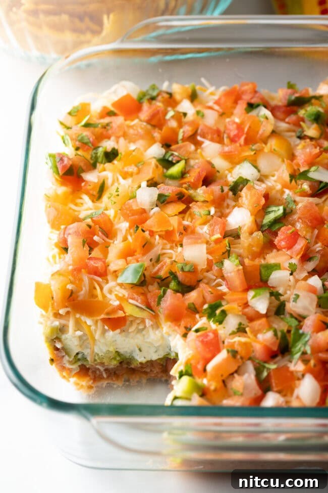 Fiesta Bean Stack 10 View of glass dish with portion missing, showing all 5 layers of the Mexican bean dip.