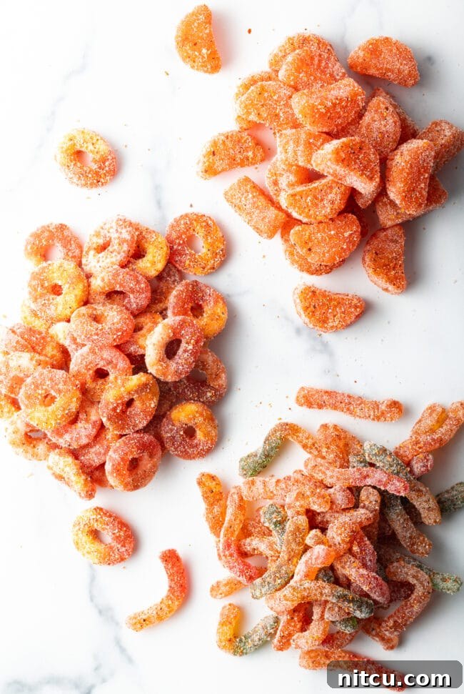 Spicy Chamoy Mexican Candies 3 Top down view of four piles of dulces enchilados gummy candies, each now vibrantly coated with chamoy and tajin seasoning.