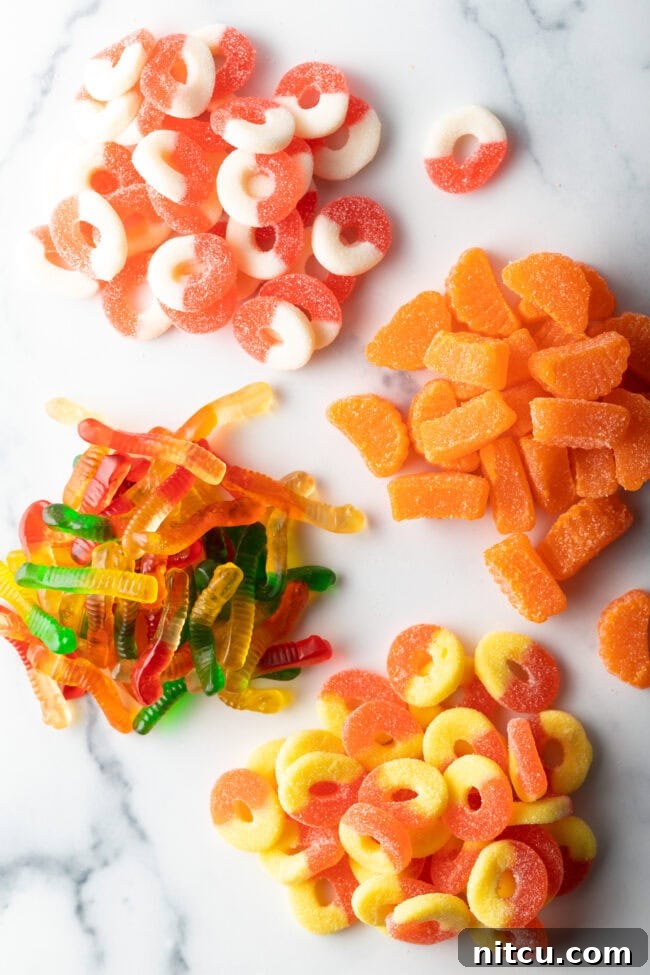 Spicy Chamoy Mexican Candies 5 Top down view of four piles of different gummy candies: White and orange circles, orange slices, yellow and orange circles, before coating.