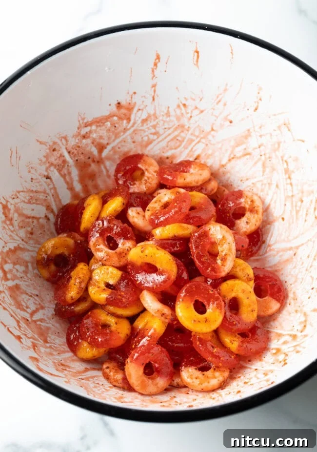 Spicy Chamoy Mexican Candies 7 Gummy fruit rings tossed in sauce and seasoning in a white bowl, glistening and ready for drying.