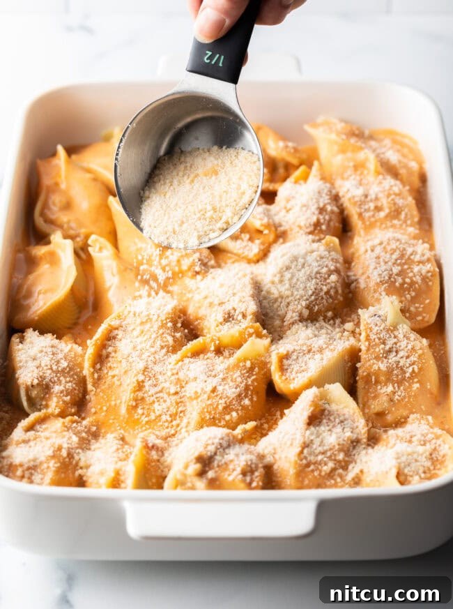Ocean's Bounty Stuffed Shells 14 Adding grated parmesan cheese to the baking dish with stuffed pasta.