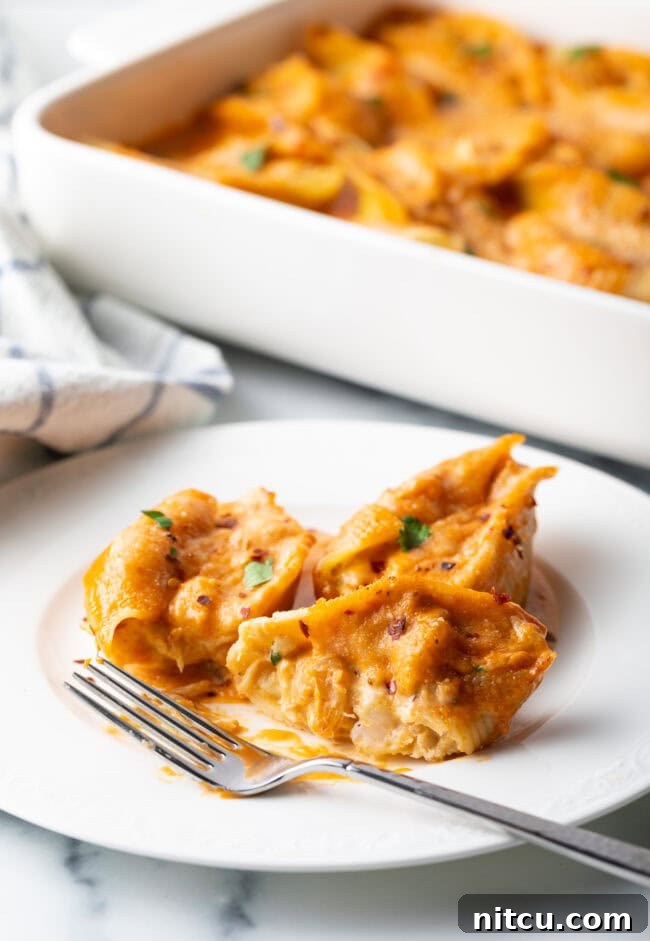 Ocean's Bounty Stuffed Shells 4 Serving of cheesy seafood pasta on a white plate with fork.