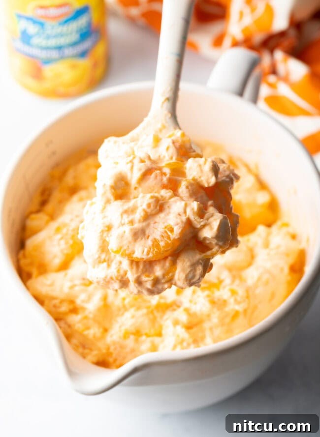 Zesty Orange Ambrosia 10 Spoon showing creamsicle fluff salad to camera.