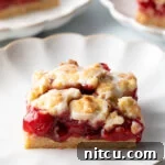Sweet Cherry Crumble Bars 14 Square piece of cherry pie bar on a white scalloped plate.
