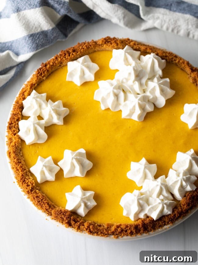 A whole, baked mango pie beautifully topped with piped clusters of whipped meringue, adding an elegant touch.