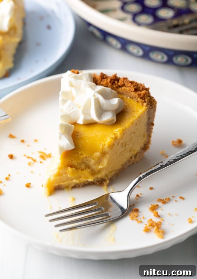 A slice of mango pie on a white plate, with a bite taken from the tip and a metal fork resting to the side, highlighting its irresistible appeal.