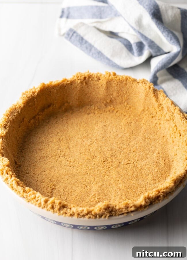 A perfectly formed graham cracker pie crust resting in a pie plate, ready for the delicious mango filling.
