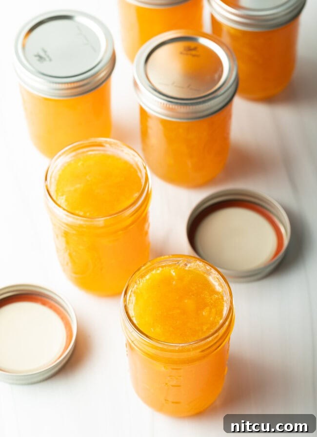 Multiple jars of peach preserves without lids, ready for sealing.