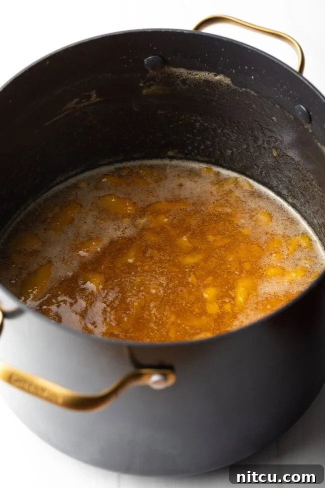 Cooking down the fruit mixture in a large black pot for preserves.