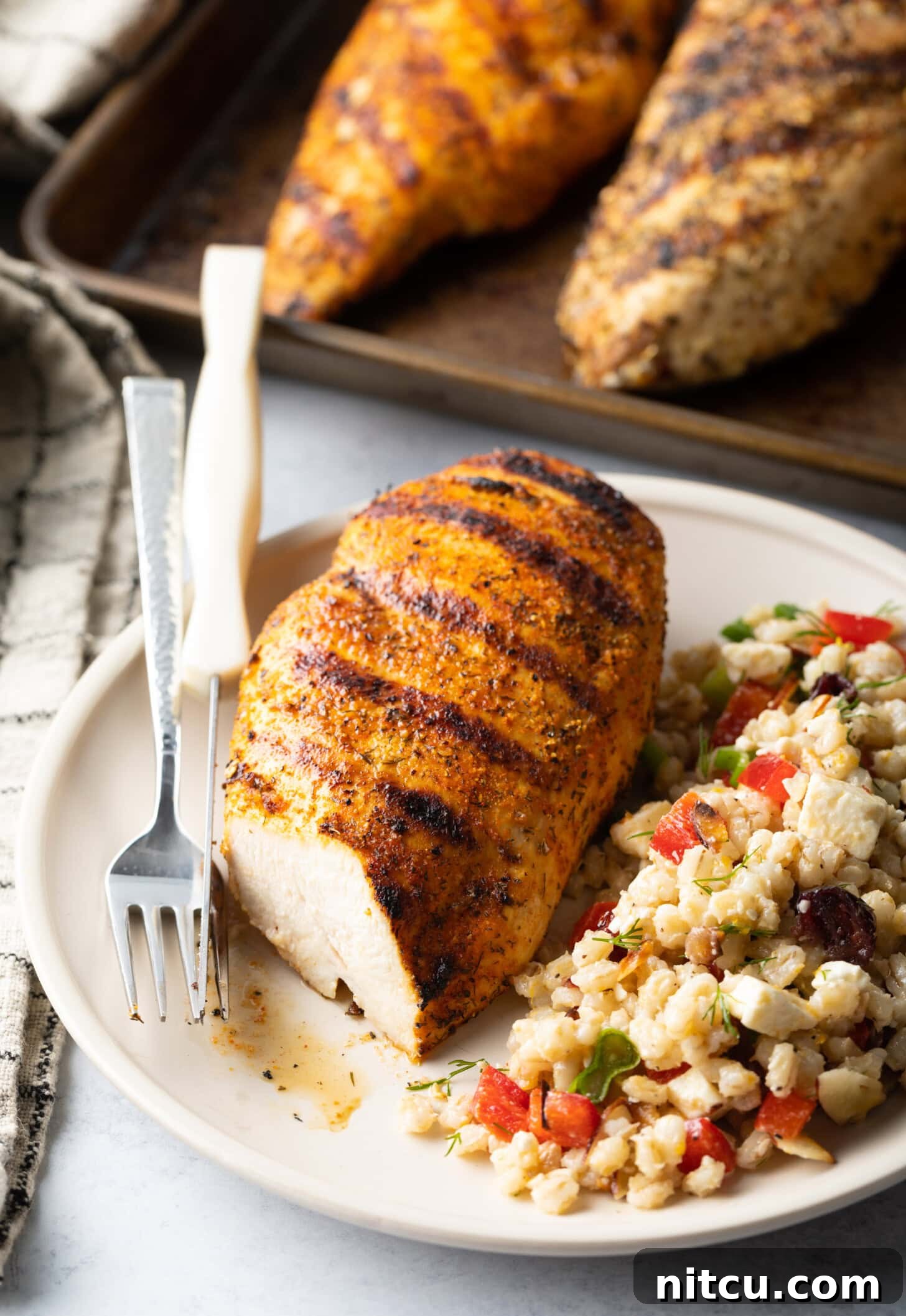 Signature Chicken Seasoning 3 Seasoned grilled chicken breast on a plate. Chicken is cut in half to show inside of the meat. Next to the chicken is a serving of bean salad.
