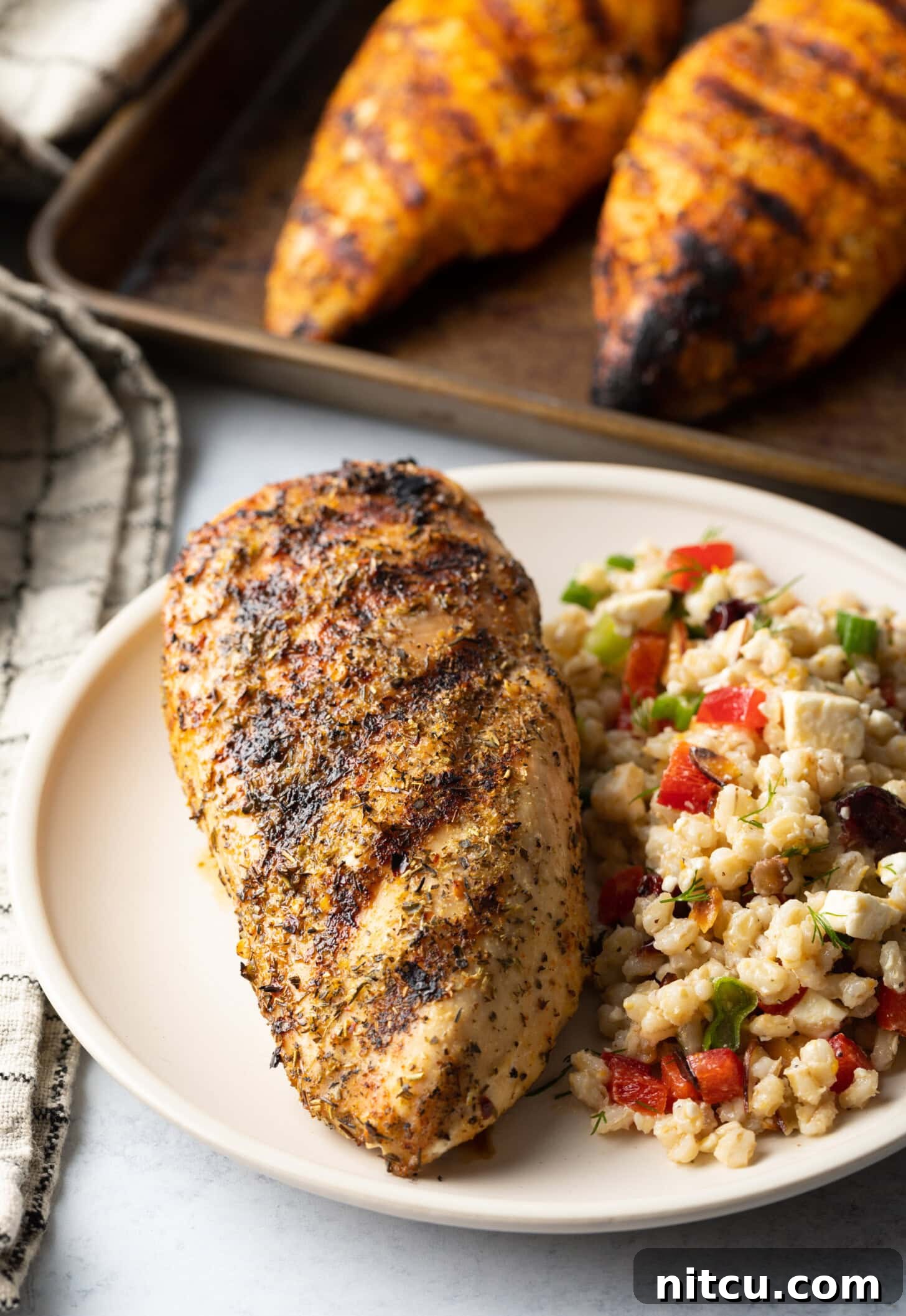 Signature Chicken Seasoning 9 Top down view one whole chicken breast seasoned and grilled, resting on a white plate next two a side of bean salad.