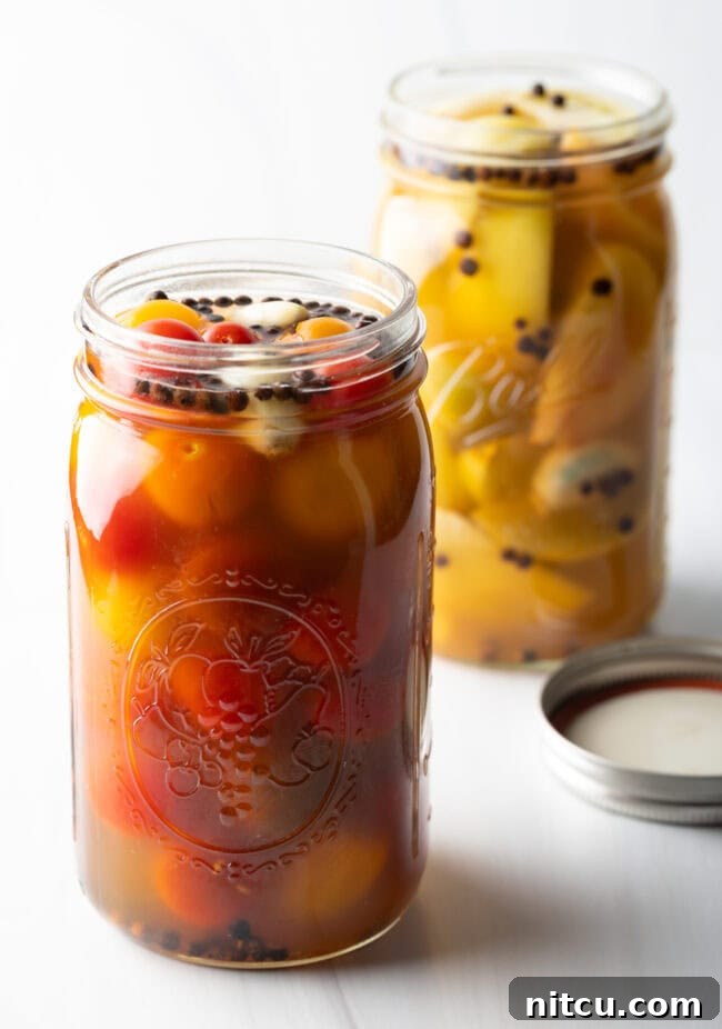 Tangy Tomato Preserves 13 Marinated pickled cherry tomatoes in a large glass jar in the foreground. Marinated pickled green tomatoes in a large glass jar in the backrground.