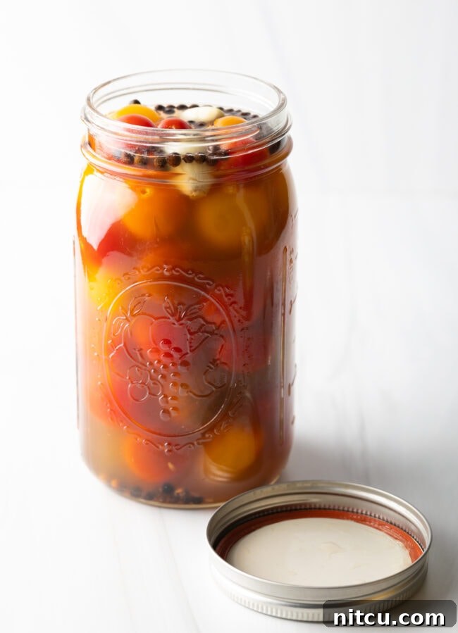 Tangy Tomato Preserves 4 Marinated pickled cherry tomatoes in a large glass jar.