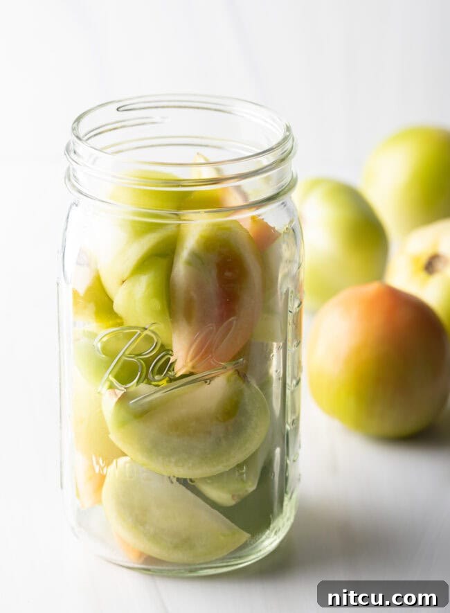 Tangy Tomato Preserves 6 Small green tomatoes in a large glass ball jar.