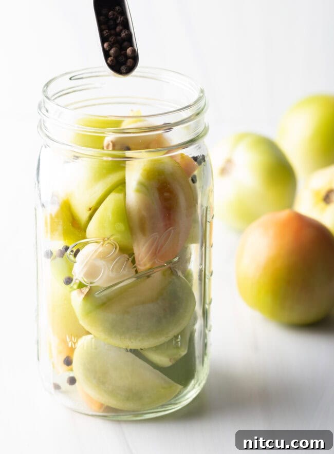 Tangy Tomato Preserves 8 Small green tomatoes in a large glass ball jar.
