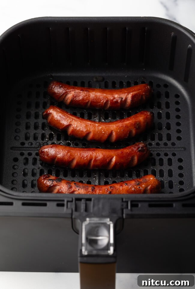 Crispy Air-Fried Franks 6 Cooked dark brown hot dogs in the fryer basket.