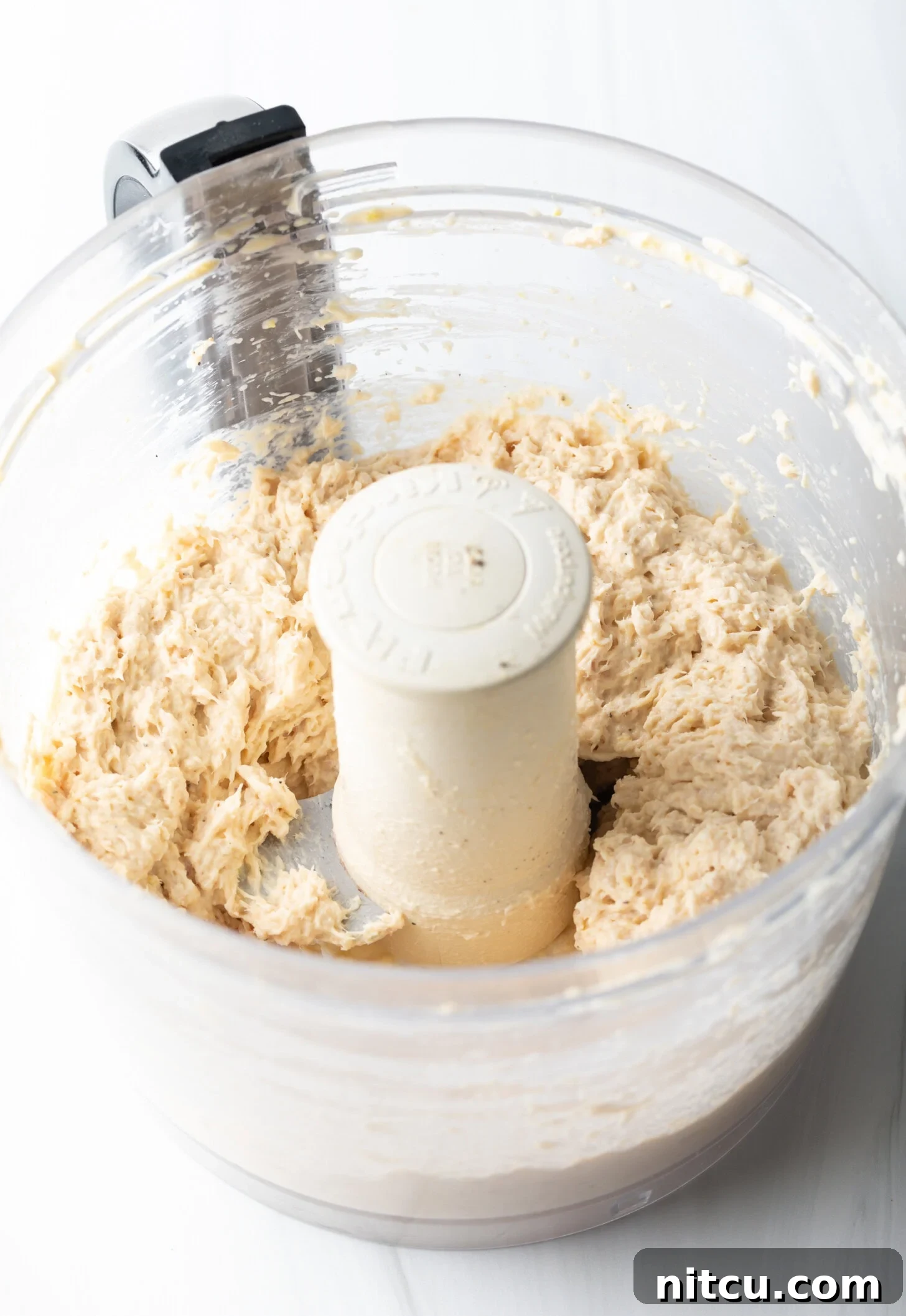 Coastal Smokehouse Dip 6 An overhead view captures the creamy, blended smoked fish dip swirling within the clear bowl of a food processor, showcasing its rich texture and readiness.