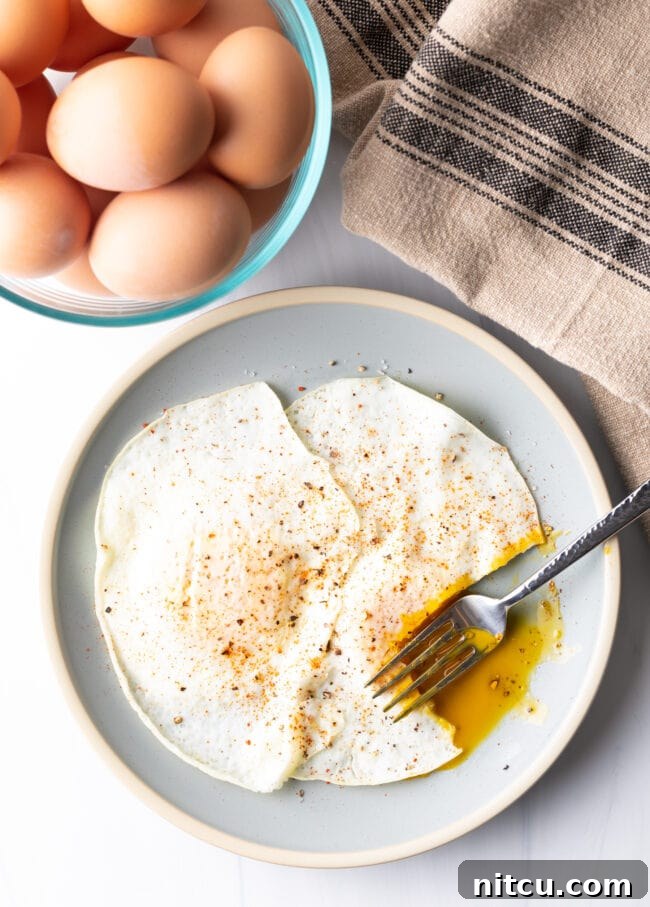 Mastering Over Easy Eggs 13 Fork cutting into the soft yolk of a gently over easy fried egg, on a light blue plate.