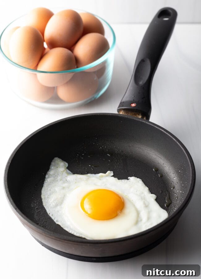 Mastering Over Easy Eggs 8 Sunny side up egg cooking in a black skillet.
