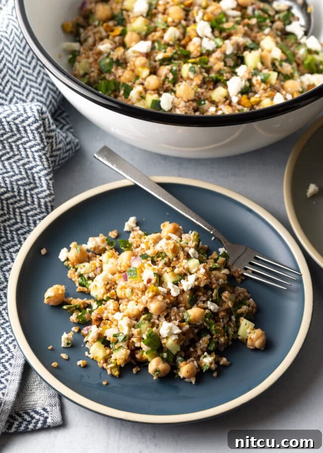 Jennifer Aniston's Go-To Bulgur Salad 11 Blue plate with a generous serving of Jennifer Aniston bulgur wheat salad, with a metal fork on the plate.
