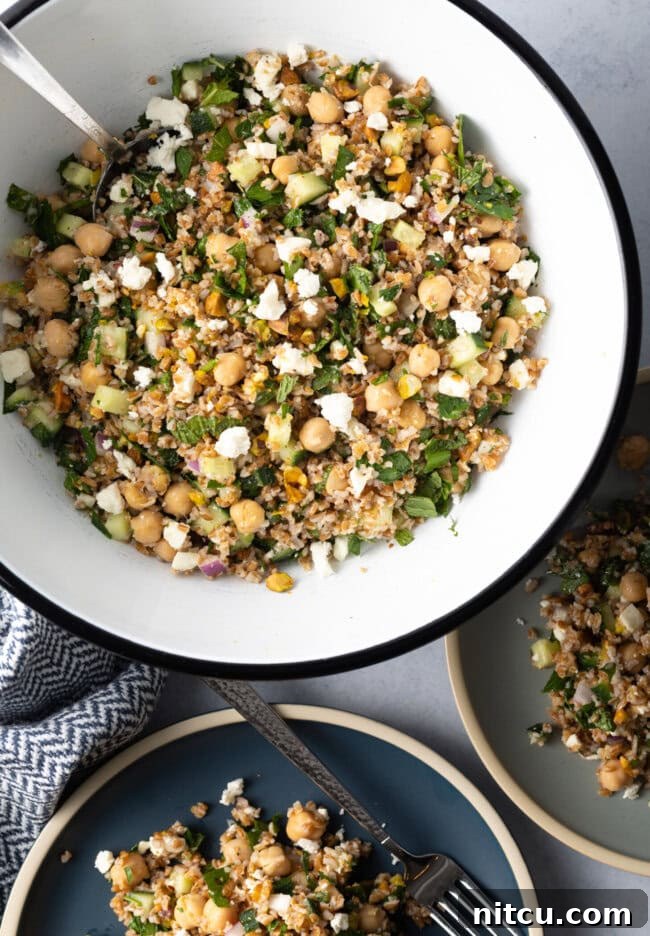 Jennifer Aniston's Go-To Bulgur Salad 4 Large white bowl filled with bulgur wheat, veggies, and feta salad.