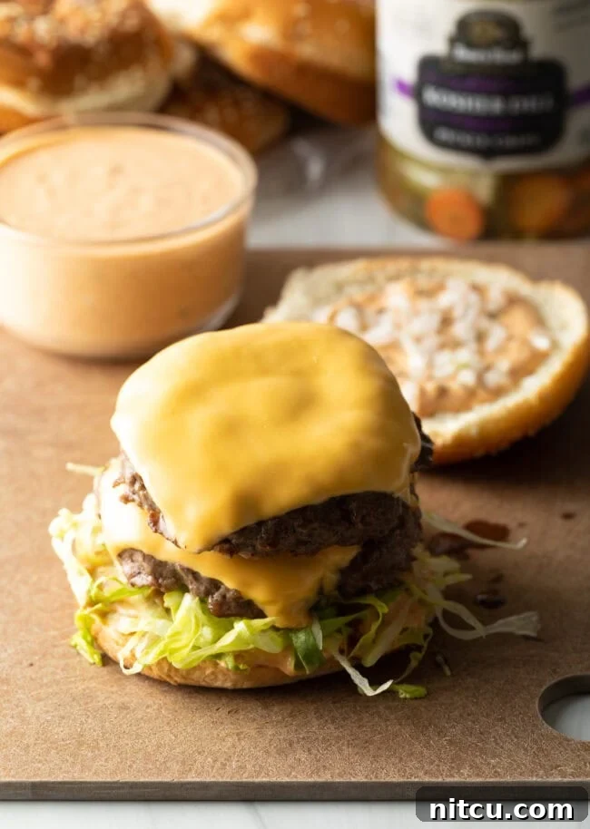 A cheeseburger patty perfectly placed on a bun, topped with crisp shredded lettuce, ready for the next layer.