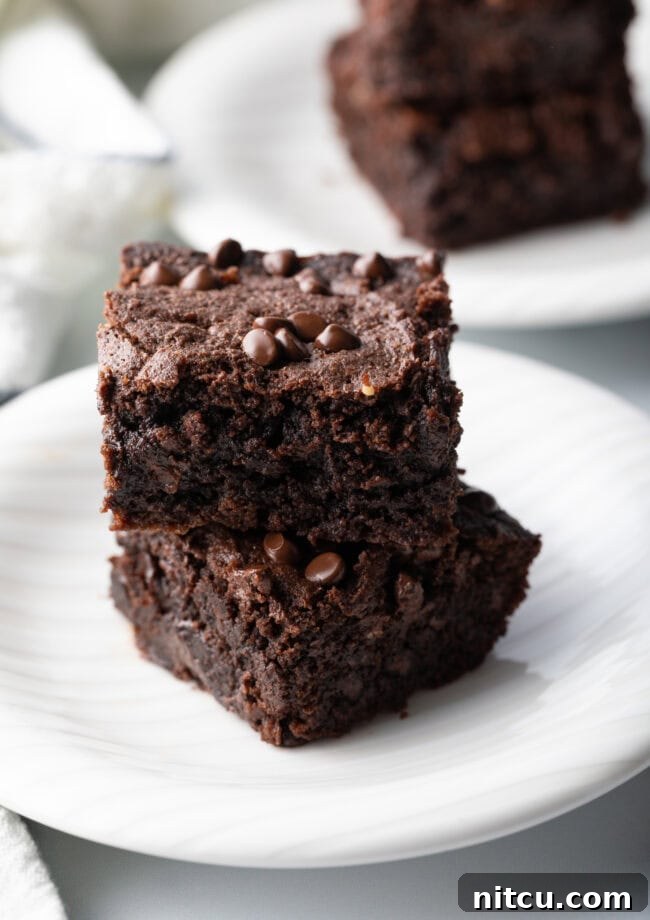 Glow-Up Protein Brownies 11 Two brownies with protein collagen stacked on a white plate, highlighting their rich chocolate flavor and tempting texture.