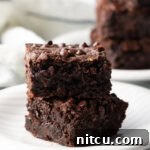 Two collagen protein brownies stacked on a white plate, ready to be served.