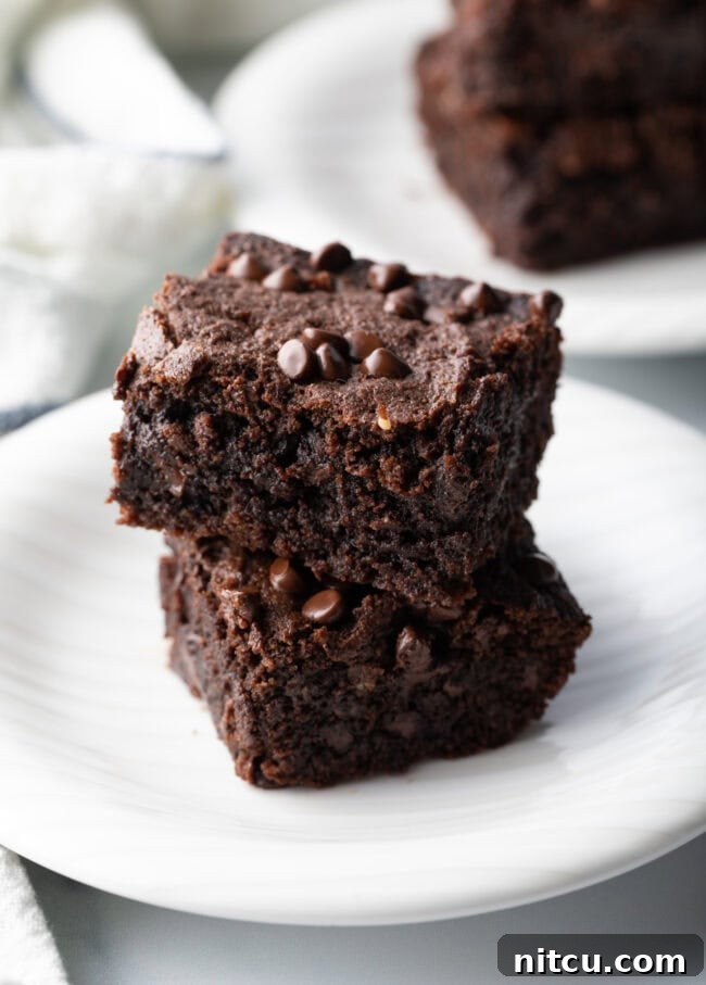 Glow-Up Protein Brownies 3 Two protein brownies on a plate, highlighting their rich, dark chocolate color and enticing texture.