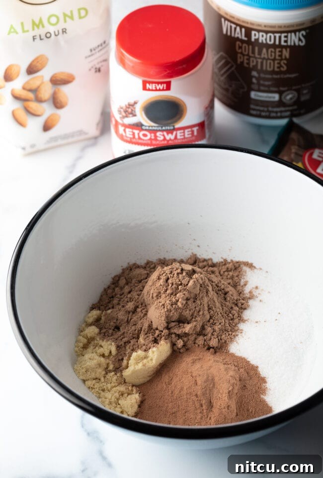 Glow-Up Protein Brownies 6 Dry ingredients in a white bowl: cocoa powder, collagen, sweetener alternative, and almond flour, perfectly measured and ready to mix.