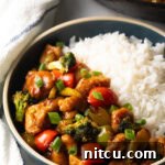 A delicious bowl featuring half savory chicken stir-fry and half fluffy white rice.