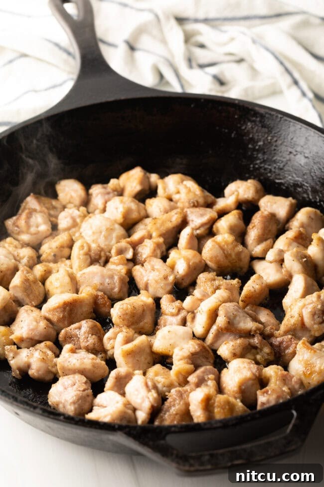 Hunan Firecracker Chicken 7 Succulent chopped chicken thigh pieces sizzle and stir-fry in a hot cast iron skillet, browning beautifully for the Hunan Chicken.