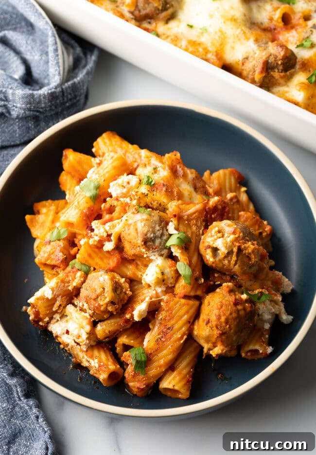 One-Pan Meatball Casserole 4 Dark gray plate with a generous portion of baked meatball casserole with pasta and cheese.