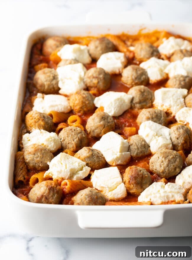 One-Pan Meatball Casserole 7 Layers of meatballs and chunks of cream cheese in marinara sauce, in white baking dish.