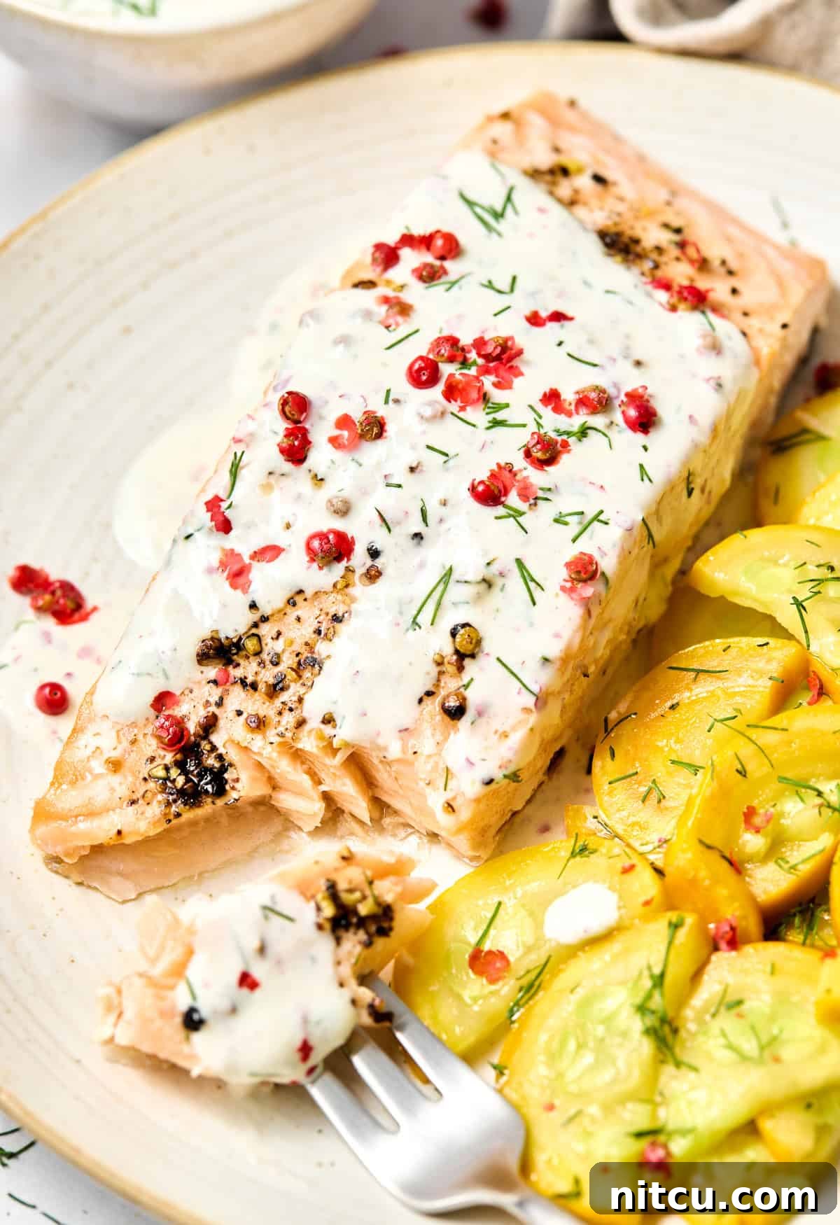 Oven Roasted Salmon #ASpicyPerspective #Salmon #RoastedSalmon #OvenRoastedSalmon #RoastedSalmonRecipe #PeppercornSauce #PinkPeppercorn #PinkPeppercornSauce #MothersDay Plate with Oven Roasted Salmon with Pink Peppercorn Sauce and yellow squash on the side. A few bites have been taken out of the fish to show the flaky inside.