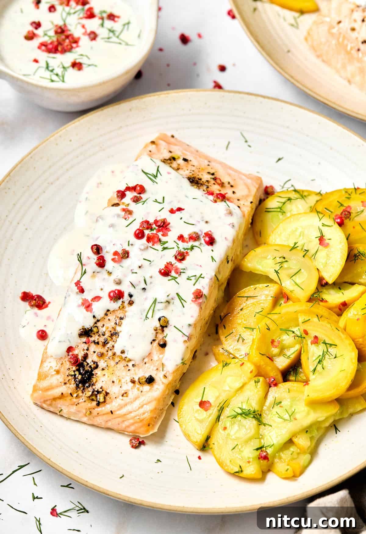 Roasted Salmon with Pink Peppercorn Sauce #ASpicyPerspective #Salmon #RoastedSalmon #OvenRoastedSalmon #RoastedSalmonRecipe #PeppercornSauce #PinkPeppercorn #PinkPeppercornSauce #MothersDay Baked salmon on a plate with pink peppercorn sauce and fresh whole pink peppercorns on top. A serving of yellow cooked squash is on the side.
