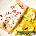 Roasted salmon with pink peppercorn sauce and yellow squash on plate