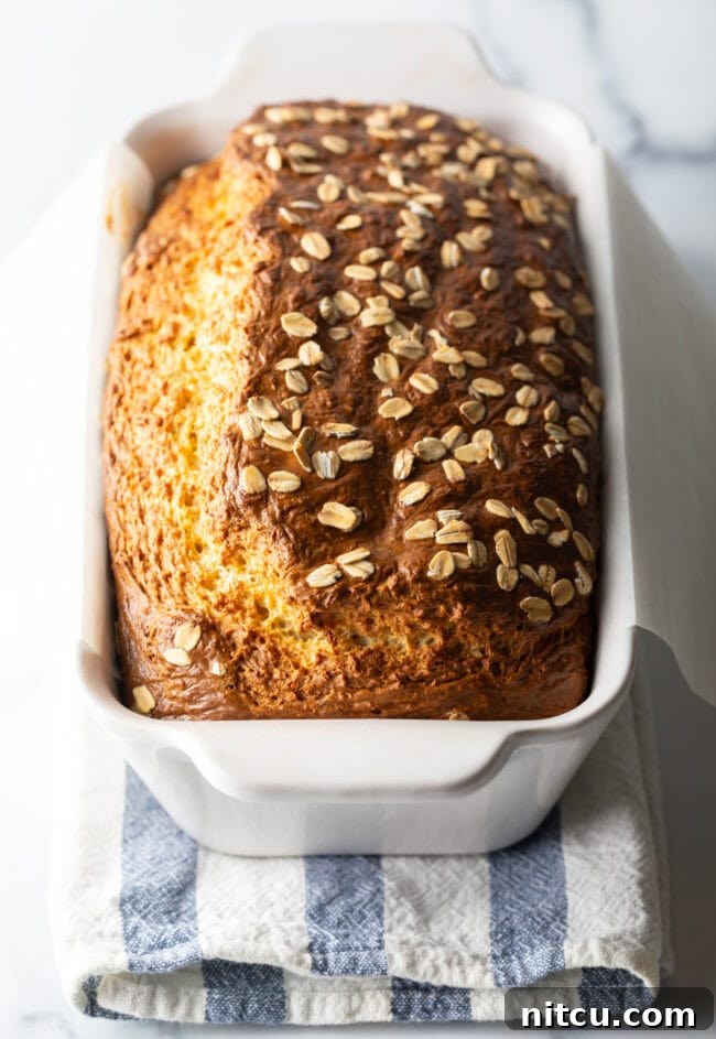 Full loaf of cottage cheese bread with oats in a white loaf pan.