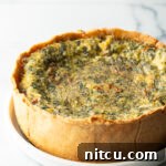 Garden Medley Deep Dish Quiche 15 Baked veggie quiche with a deep dish crush on a white round plate.
