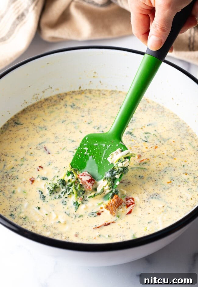 Garden Medley Deep Dish Quiche 8 A white mixing bowl filled with the vibrant egg and veggie quiche filling, being stirred with a green spatula, showing the rich texture before baking.
