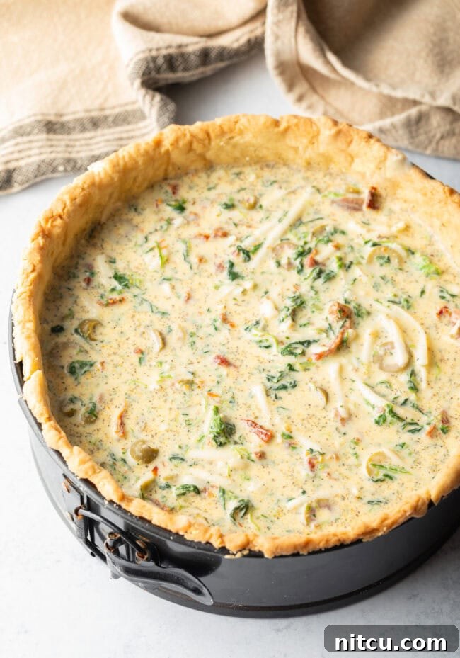 Garden Medley Deep Dish Quiche 9 Top-down view of the unbaked egg and vegetable mixture settled into a deep dish pie crust within a springform pan, ready for its final bake.