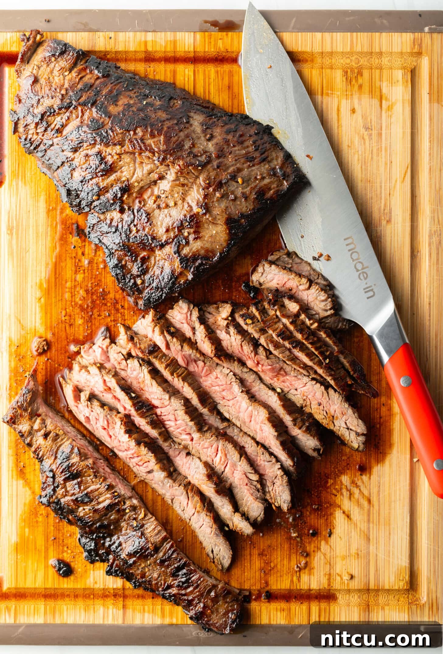 Thin Skirt Steak Delights 3 Seared steak sliced into thin strips on a wood cutting board, large knife to the side.