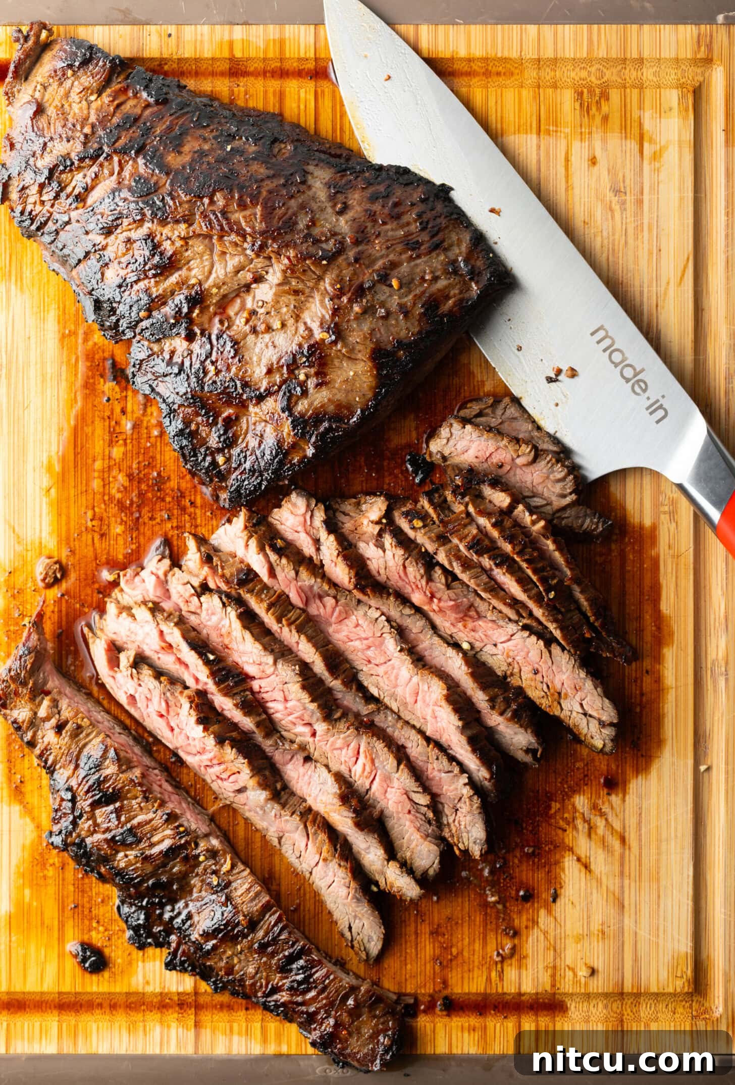Thin Skirt Steak Delights 8 Seared steak sliced into thin strips on a wood cutting board, large knife to the side.