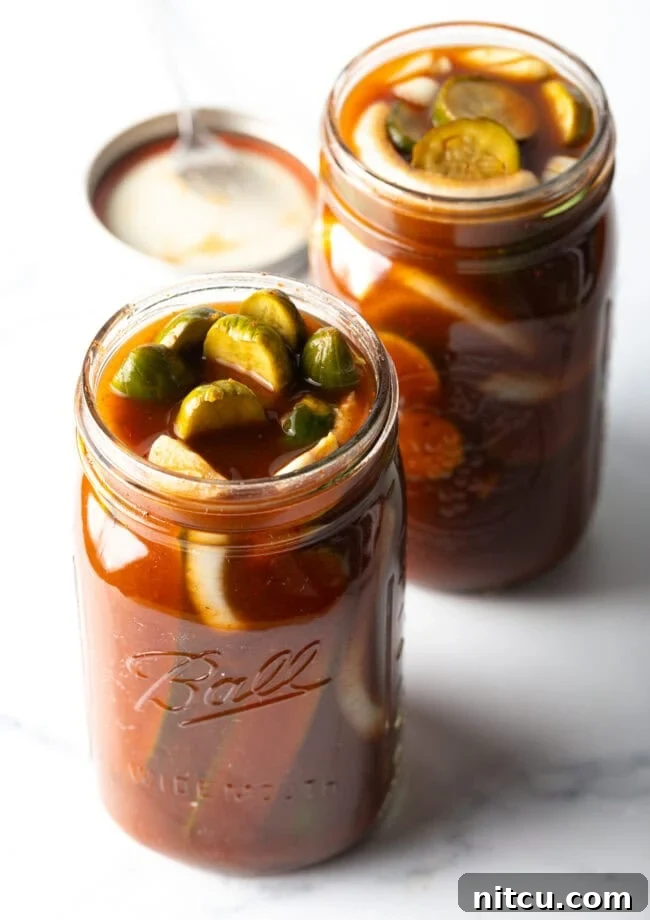 Chamoy Drenched Pickles 4 Two glass jars filled with cucumber slices and chamoy seasonings.