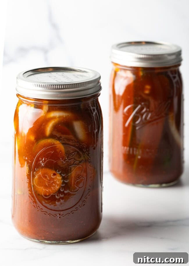 Chamoy Drenched Pickles 9 Two glass jars filled with cucumber slices and chamoy seasonings.