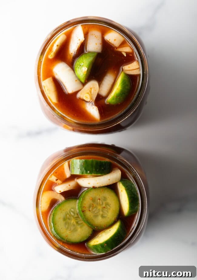 Chamoy Drenched Pickles 10 Two glass jars filled with cucumber slices and chamoy seasonings.