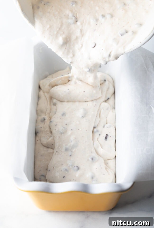 Pouring batter into a ceramic loaf pan.