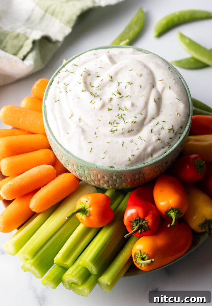 Bowl of cottage cheese dip surrounded by a sunburst of fresh veggies like carrots, mini bell peppers, celery, and green pepper slices.