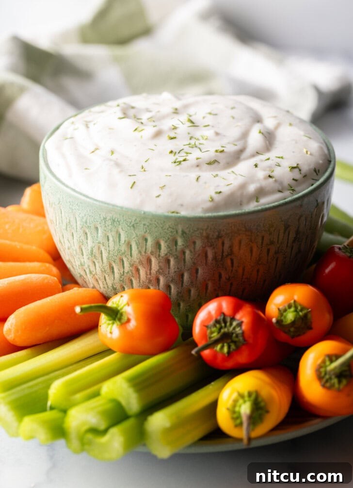 Bowl of cottage cheese dip surrounded by a sunburst of fresh veggies like carrots, mini bell peppers, celery, and green pepper slices.